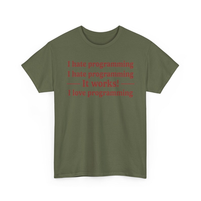 K&ouml;nnte beinhalten: Ein olivgr&uuml;nes Kurzarm-T-Shirt mit rotem Textaufdruck: I hate programming, I hate programming, &mdash; It works! &mdash;, I love programming. Das Shirt hat einen Rundhalsausschnitt und eine normale Passform, wobei der Text mittig auf der Brust platziert ist.