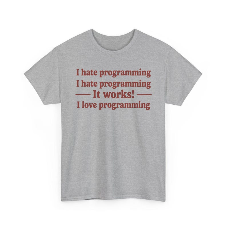 K&ouml;nnte beinhalten: Ein graumeliertes Kurzarm-T-Shirt mit dunkelrotem Textaufdruck auf der Vorderseite. Der Text lautet: I hate programming, I hate programming, &mdash; It works! &mdash;, I love programming. Das T-Shirt hat einen Rundhalsausschnitt und eine Standardpassform.