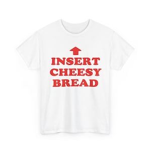 May include: A white short-sleeved t-shirt featuring a red upward-pointing arrow graphic above the red text that reads INSERT CHEESY BREAD. The shirt has a crew neckline and a standard fit, displaying the bold red lettering centered on the chest.