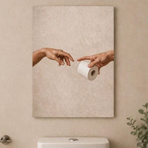 May include: A framed print depicting two hands reaching towards each other, one holding a roll of toilet paper. The artwork is mounted above a white toilet, with a roll of toilet paper on a holder to the left. A vase with greenery is on the right.