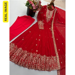 May include: A vibrant red long-sleeved floor-length dress featuring intricate gold embroidery and mirror work along the neckline, cuffs, and hem. The set includes matching red trousers and a sheer red dupatta with gold decorative borders.