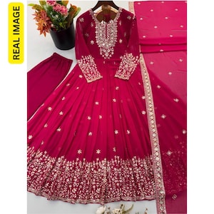 May include: A magenta long-sleeved floor-length dress featuring intricate silver embroidery around the neckline, cuffs, and hem. The dress includes a matching magenta pair of trousers and a coordinating magenta dupatta with silver floral accents.