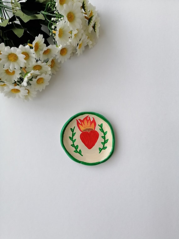 A hand-sculpted clay dish shaped like a flaming heart — equal parts functional ring holder and tiny art object for your vanity.