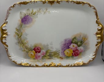 Plato antiguo de porcelana de Limoges pintado a mano con motivos florales y borde dorado festoneado.