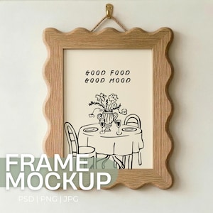 May include: A framed print with the text "GOOD FOOD GOOD MOOD" above a black and white illustration of a table setting with flowers. The frame is light brown with a wavy edge, and is hanging from a gold hook.