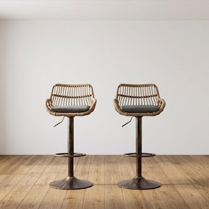 May include: Two rattan bar stools with gray cushions and adjustable height. The stools have a dark brown metal base and a woven backrest. The stools are on a hardwood floor.