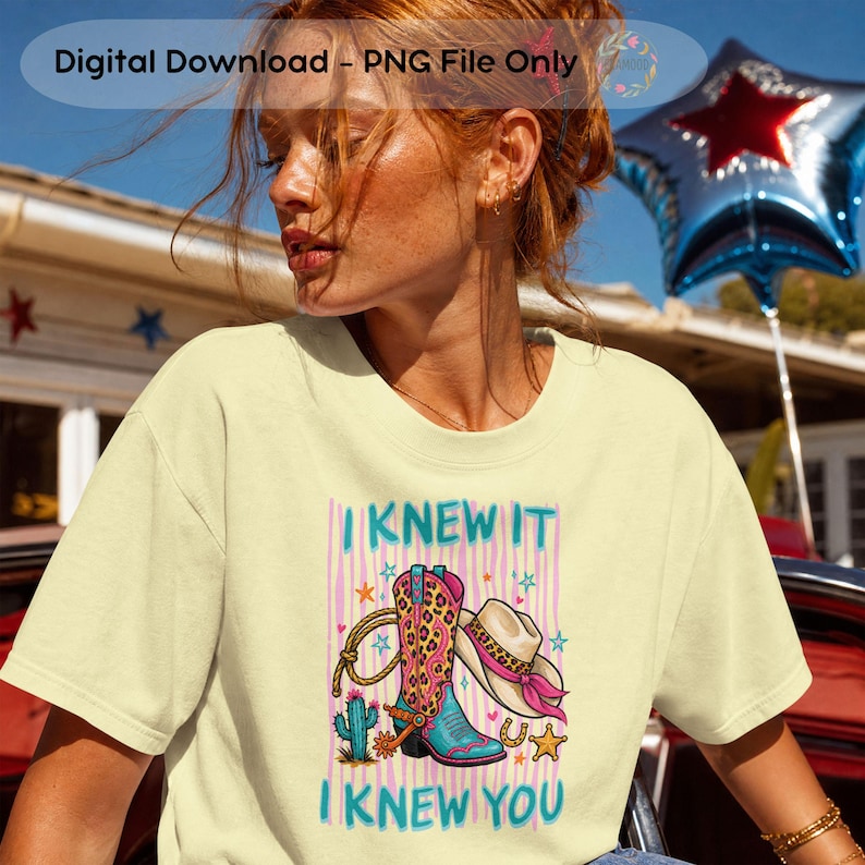 Puede incluir: Una camiseta de color amarillo p&aacute;lido con un estampado gr&aacute;fico de una bota de vaquero con estampado de leopardo, un sombrero de vaquero con una banda rosa, un lazo, un cactus y estrellas. El texto "I KNEW IT" y "I KNEW YOU" aparece en verde azulado.