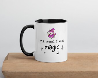 May include: White ceramic mug with a black interior and handle. The mug features a cartoon cat wearing a witch hat and robe, with the text "f*ck normal I want magic" and star graphics.