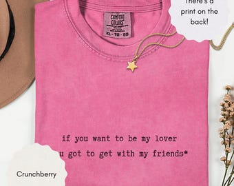 May include: A pink short-sleeved t-shirt with a crew neckline. The front features black text that reads, if you want to be my lover u got to get with my friends*. The interior neck label displays the brand name Comfort Colors and size XL.