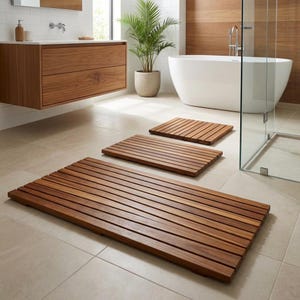Könnte beinhalten: Drei Holz-Badematten in verschiedenen Größen sind auf einem gefliesten Boden in einem Badezimmer angeordnet. Die Matten haben eine natürliche Holzoberfläche und ein Lamellendesign. Eine weiße Badewanne und eine Topfpflanze sind im Hintergrund zu sehen.