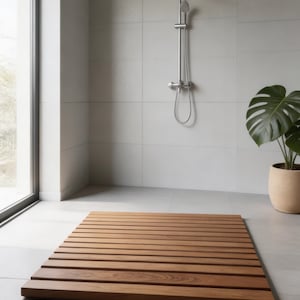 May include: A rectangular wooden bath mat with horizontal slats, in a warm brown hue. It rests on a grey tiled floor. A silver shower fixture is mounted on the wall behind the mat. The mat measures approximately 100 cm x 60 cm.