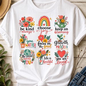 Pode incluir: Uma t-shirt branca com uma grelha de nove ilustrações coloridas com textos inspiradores como be kind always, choose joy, keep on blooming, you matter, focus on the good, growth is a process, the world needs you, life is beautiful e you are loved.
