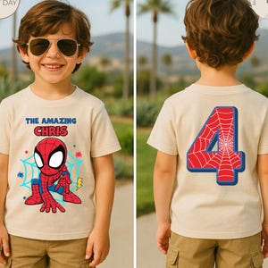 Puede incluir: Una camiseta beige con un dise&ntilde;o de Spider-Man en la parte delantera y un gran n&uacute;mero 4 en la parte trasera. El dise&ntilde;o frontal incluye el texto "THE AMAZING CHRIS" encima de la ilustraci&oacute;n de Spider-Man. La camiseta se combina con pantalones cortos color caqui.