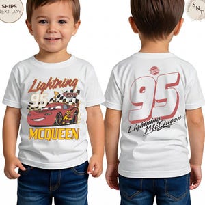 May include: White t-shirt featuring Lightning McQueen from the Cars movie. The front displays the character with the text "Lightning 95 McQueen." The back of the shirt shows the number "95" and "Lightning McQueen" in red.