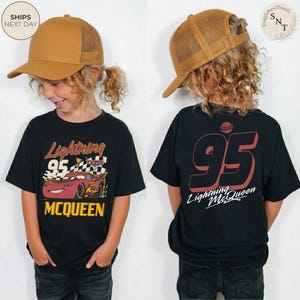 May include: Black Lightning McQueen t-shirt with a graphic of the character and the number 95. The shirt has the text "Lightning McQueen" and "MCQUEEN" in yellow. The child is wearing a brown trucker hat.