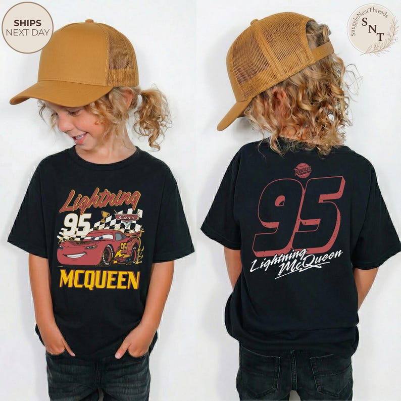 May include: Black Lightning McQueen t-shirt with a graphic of the character and the number 95. The shirt has the text "Lightning McQueen" and "MCQUEEN" in yellow. The child is wearing a brown trucker hat.