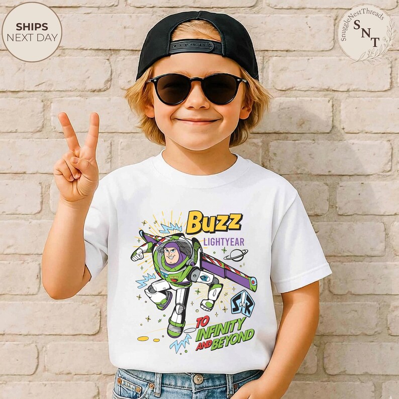 Puede incluir: Camiseta blanca con un gr&aacute;fico colorido de Buzz Lightyear, con el texto "Buzz Lightyear" y "To Infinity and Beyond". El dise&ntilde;o incluye elementos espaciales. La camiseta la lleva un ni&ntilde;o.