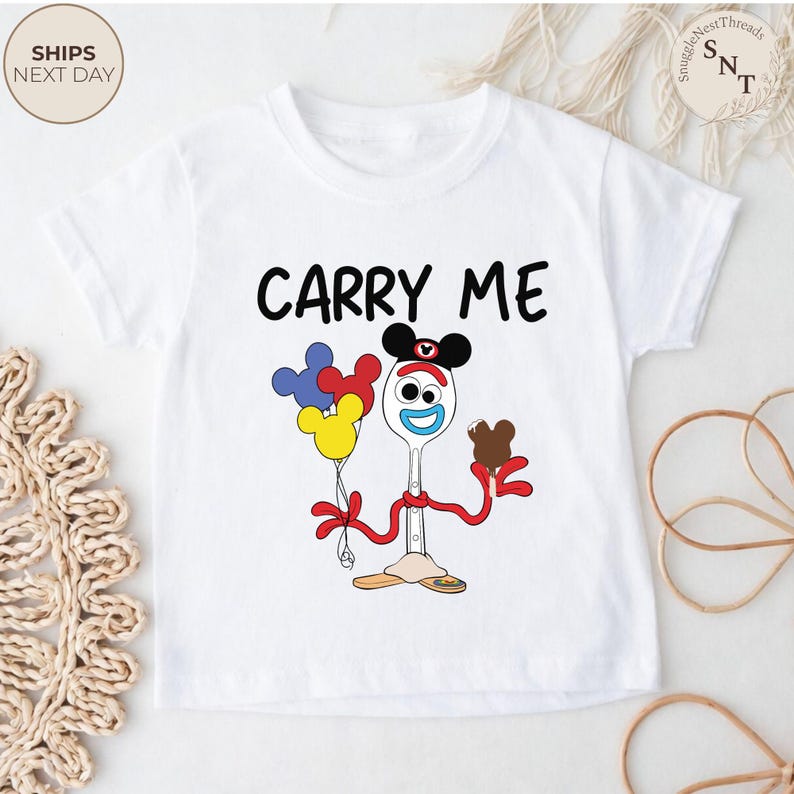 May include: White toddler t-shirt with the text "CARRY ME" in black. The shirt features a cartoon character holding balloons and a chocolate ice cream cone. The character is a spoon with a face and Mickey Mouse ears.