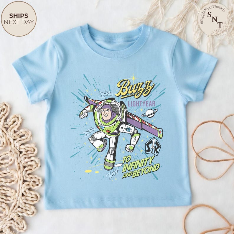 Puede incluir: Camiseta azul claro con Buzz Lightyear de Toy Story. El gr&aacute;fico muestra a Buzz con su traje espacial con las palabras "Buzz Lightyear" y "To Infinity and Beyond". La camiseta tiene mangas cortas.
