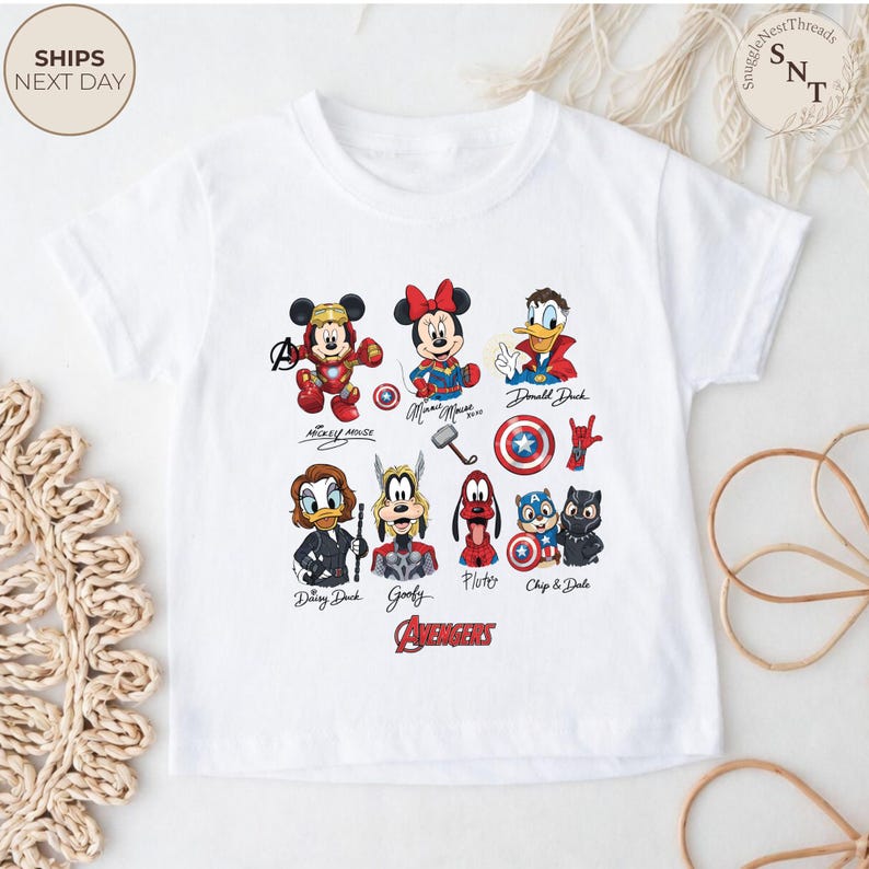 May include: White t-shirt featuring a colorful graphic of Disney characters in Avengers-themed designs. Characters include Mickey Mouse, Minnie Mouse, Donald Duck, Daisy Duck, Goofy, Pluto, Chip and Dale. The word "Avengers" is printed in red.