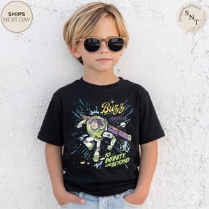 Puede incluir: Una camiseta negra con un gr&aacute;fico de Buzz Lightyear de Toy Story. El dise&ntilde;o incluye el texto "Buzz Lightyear" y "To Infinity and Beyond" en una colorida ilustraci&oacute;n con tem&aacute;tica espacial. La camiseta la lleva un ni&ntilde;o.