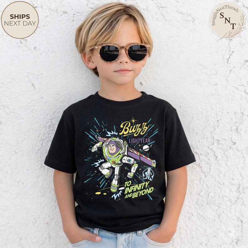 Puede incluir: Una camiseta negra con un gr&aacute;fico de Buzz Lightyear de Toy Story. El dise&ntilde;o incluye el texto "Buzz Lightyear" y "To Infinity and Beyond" en una colorida ilustraci&oacute;n con tem&aacute;tica espacial. La camiseta la lleva un ni&ntilde;o.
