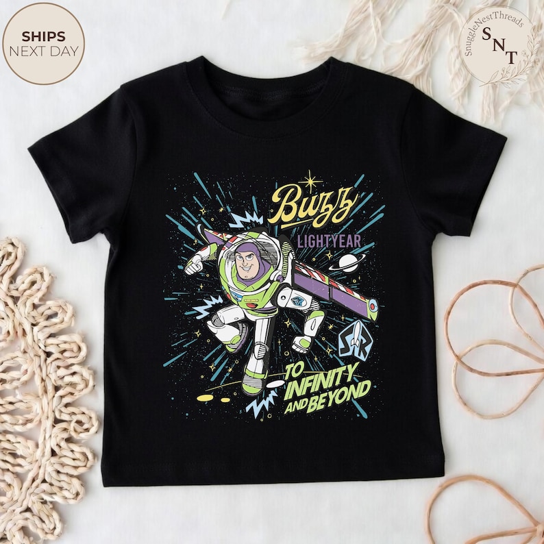 Puede incluir: Camiseta negra con un gr&aacute;fico colorido de Buzz Lightyear en movimiento. El dise&ntilde;o incluye el texto "Buzz Lightyear" y "To Infinity and Beyond". Una prenda de vestir para ni&ntilde;os.