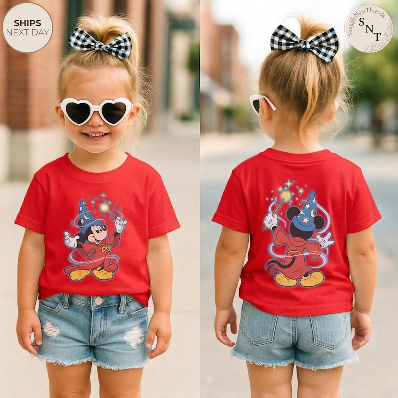 Op de afbeelding: Rood T-shirt met een cartoon Mickey Mouse tovenaar ontwerp, met een blauwe hoed en een toverstaf. Het shirt wordt gedragen met een spijkerbroek. De achterkant van het shirt heeft ook hetzelfde Mickey Mouse tovenaar ontwerp.