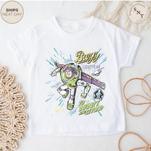 Puede incluir: Camiseta blanca con un gr&aacute;fico de Buzz Lightyear. El dise&ntilde;o incluye el texto "Buzz Lightyear" y "&iexcl;Hasta el infinito y m&aacute;s all&aacute;!" con una colorida ilustraci&oacute;n del personaje en acci&oacute;n.