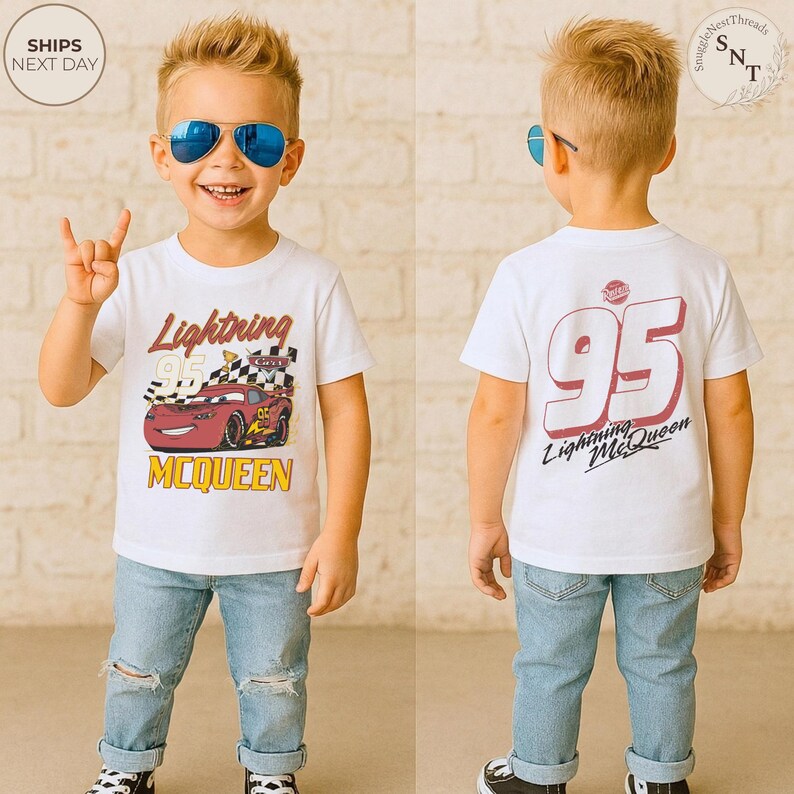 May include: A white t-shirt featuring Lightning McQueen from the Cars movie. The front of the shirt displays the character with the text "Lightning McQueen" and "95". The back of the shirt has a large "95" and "Lightning McQueen" text. The child is wearing blue jeans.