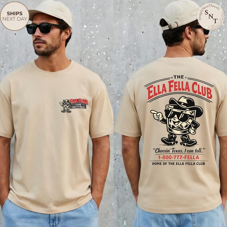 Puede incluir: Camiseta beige de manga corta con un peque&ntilde;o logotipo en la parte delantera y un gr&aacute;fico m&aacute;s grande en la parte trasera. El gr&aacute;fico trasero presenta un vaso de whisky de dibujos animados con sombrero de vaquero y gafas de sol, con el texto "The Ella Fella Club."