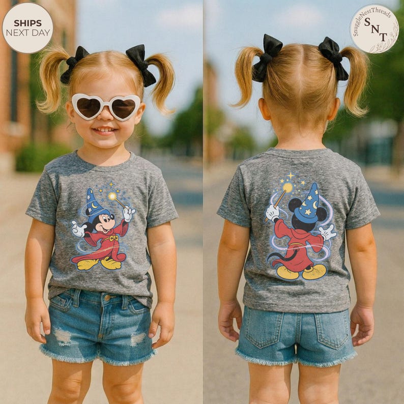 Op de afbeelding: Grijs t-shirt met een cartoon Mickey Mouse tovenaar ontwerp, voor- en achteraanzicht. Het personage houdt een toverstaf vast. Het shirt wordt gedragen met een spijkerbroek. De tekst "SHIPS NEXT DAY" is zichtbaar.