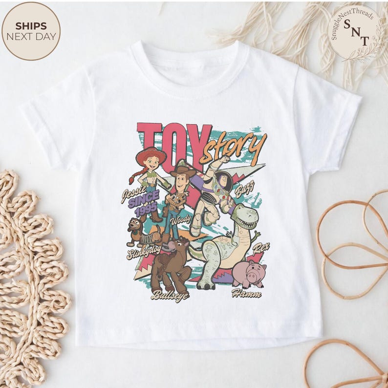 Puede incluir: Una camiseta blanca de manga corta con un estampado gr&aacute;fico colorido de los personajes de Toy Story, incluyendo a Jessie, Woody, Buzz Lightyear, Slinky Dog, Bullseye, Rex y Hamm. El dise&ntilde;o incluye el texto Toy Story y los nombres.