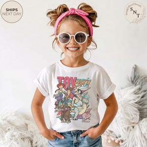 Puede incluir: Una camiseta blanca de manga corta con un estampado gr&aacute;fico colorido de los personajes de Toy Story, incluyendo a Woody, Buzz Lightyear, Jessie, Rex, Slinky Dog, Bullseye y Hamm, con el texto Toy Story y los nombres de los personajes.