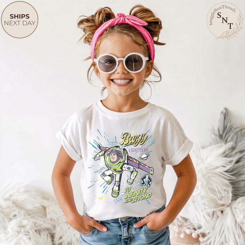 Puede incluir: Una camiseta blanca con un gr&aacute;fico de Buzz Lightyear, el texto "Buzz Lightyear" y "To Infinity and Beyond". La camiseta la lleva una persona joven con gafas de sol y una diadema rosa.
