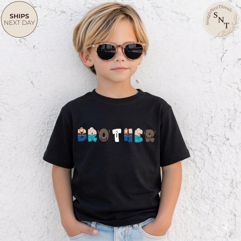 K&ouml;nnte beinhalten: Ein schwarzes T-Shirt mit dem Wort "BROTHER" in bunten, stilisierten Buchstaben. Die Buchstaben sind mit verschiedenen Mustern und Farben gestaltet, darunter Blau, Braun und Wei&szlig;. Das Shirt wird von einem Kind mit Sonnenbrille getragen.