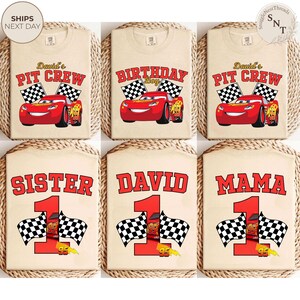 May include: Beige t-shirts with various designs featuring the character Lightning McQueen from the movie Cars. Designs include "David's Pit Crew", "Birthday Boy", "Sister", "David", and "Mama", with checkered flags and the number 1.