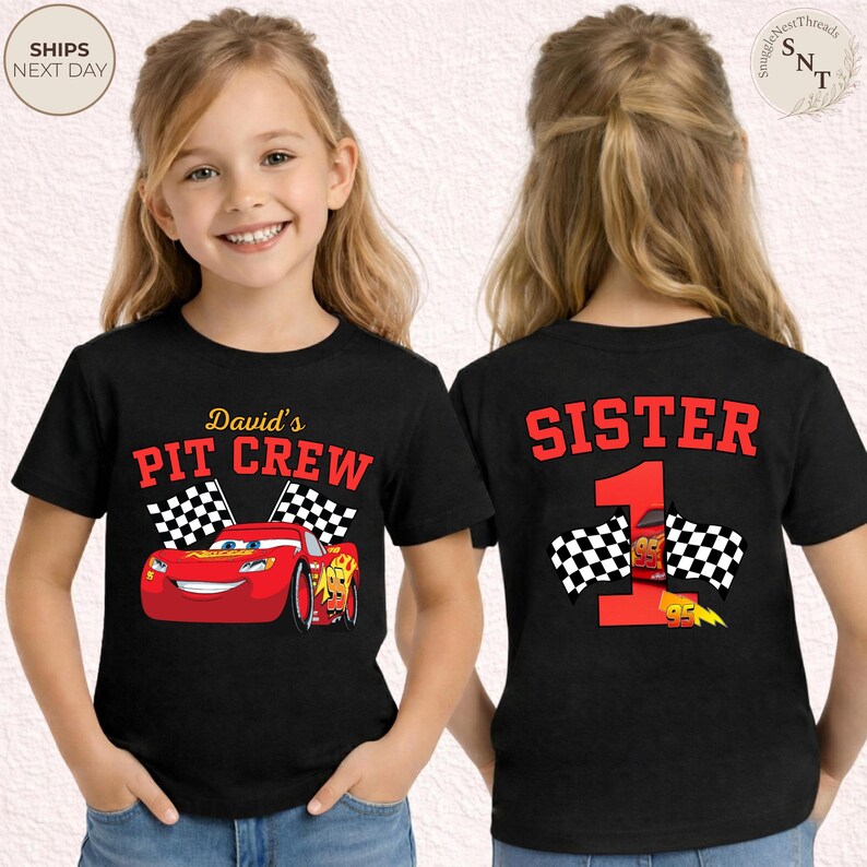 May include: Black t-shirts with a race car theme. One shirt features the text "David's PIT CREW" with a red race car and checkered flags. The other shirt says "SISTER 1" with a race car and checkered flags.