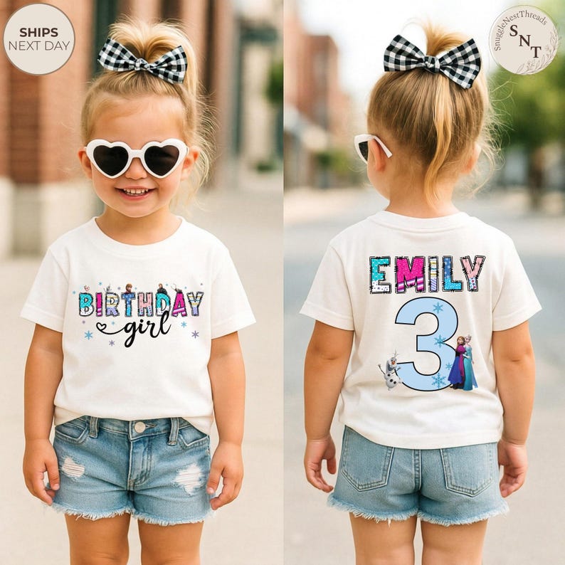 K&ouml;nnte beinhalten: Ein wei&szlig;es T-Shirt mit dem Text "BIRTHDAY girl" in bunten Buchstaben und einem Herzdesign. Auf der R&uuml;ckseite des Shirts stehen der Name "EMILY" und die Zahl "3" mit Zeichentrickfiguren. Das M&auml;dchen tr&auml;gt Jeansshorts und herzf&ouml;rmige Sonnenbrillen.