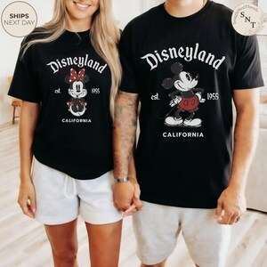 Pu&ograve; includere: T-shirt neri con il logo Disneyland, con Topolino e Minnie. Le magliette hanno la scritta "Disneyland est. 1955 CALIFORNIA". I modelli indossano pantaloncini bianchi. L'immagine &egrave; di una coppia.