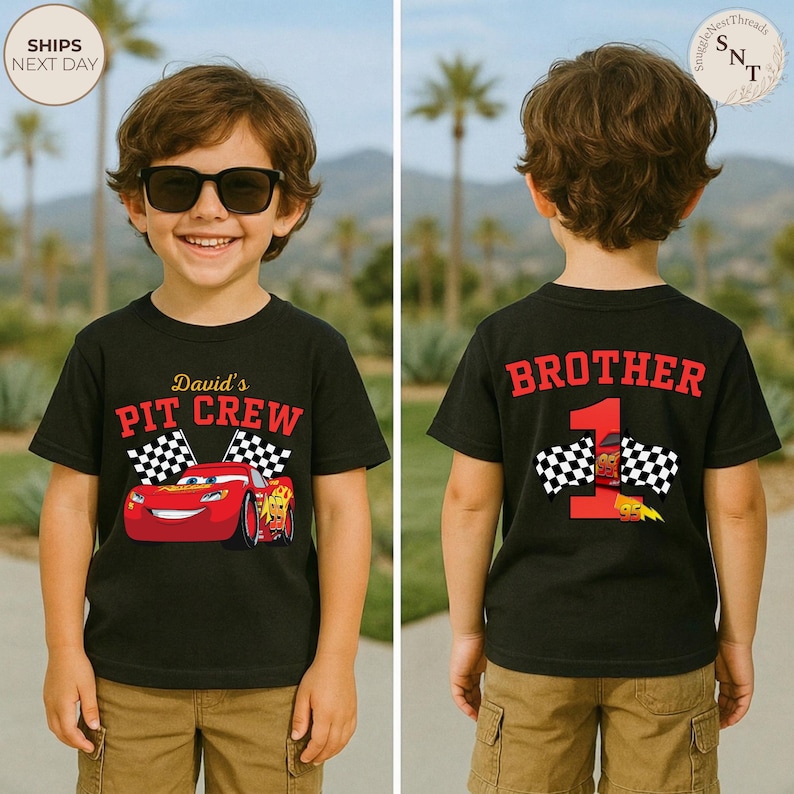 May include: A black t-shirt with a red race car graphic and the text "David's PIT CREW" on the front. The back of the shirt says "BROTHER 1" with a race car and checkered flags. The boy is wearing sunglasses and khaki shorts.