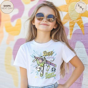 Puede incluir: Camiseta blanca con un dise&ntilde;o de Buzz Lightyear. El dise&ntilde;o muestra a Buzz con su traje espacial verde y morado, con el texto "Buzz Lightyear" y "To Infinity and Beyond".