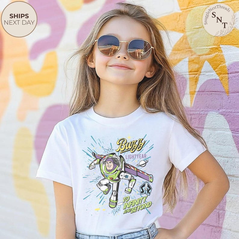 Puede incluir: Camiseta blanca con un dise&ntilde;o de Buzz Lightyear. El dise&ntilde;o muestra a Buzz con su traje espacial verde y morado, con el texto "Buzz Lightyear" y "To Infinity and Beyond".