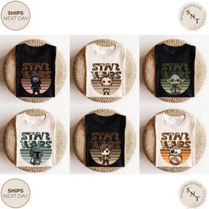 May include: Six t-shirts with Star Wars character graphics. The shirts are black and cream-colored, each featuring a different character design with the words "STAR WARS" in a retro font. The shirts are displayed on woven mats.