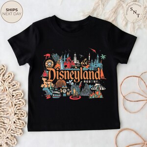 May include: Black t-shirt featuring a colorful graphic of Disneyland Resort. The design includes various park icons and the Disneyland logo in orange and red. The shirt is a classic crew neck style.