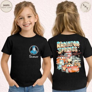 May include: Black t-shirt featuring a blue cartoon car with a checkered border and the name "Scarlet". The back of the shirt displays "Radiator Springs" and "Lightning McQueen" with various car characters.