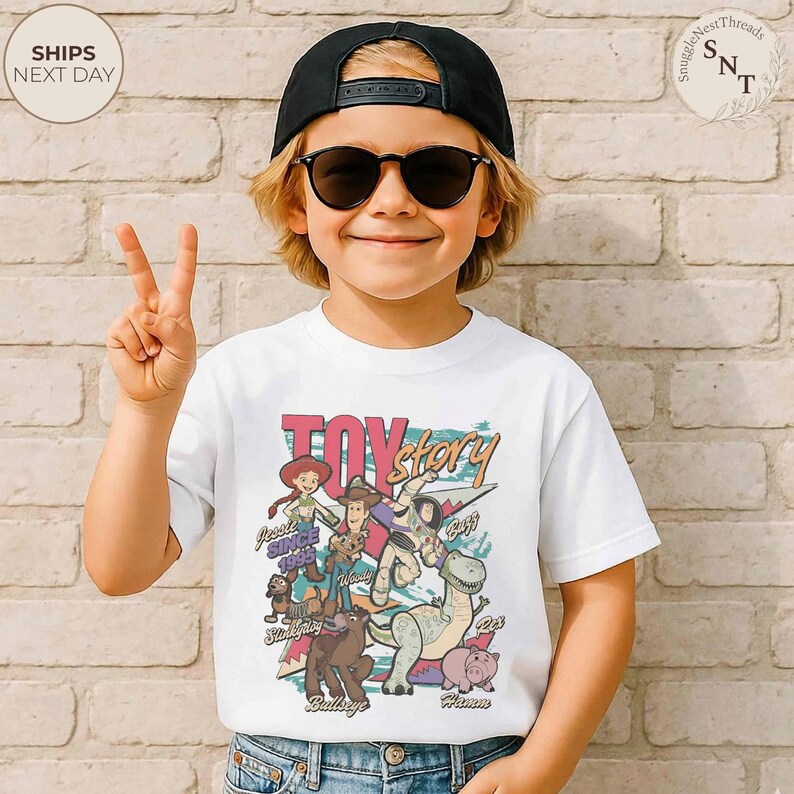 Puede incluir: Una camiseta blanca de manga corta con un estampado gr&aacute;fico colorido de los personajes de Toy Story, incluyendo a Woody, Buzz Lightyear, Jessie, Slinky Dog, Bullseye y Hamm, con el texto Toy Story y Since 1995 en una fuente de estilo retro.