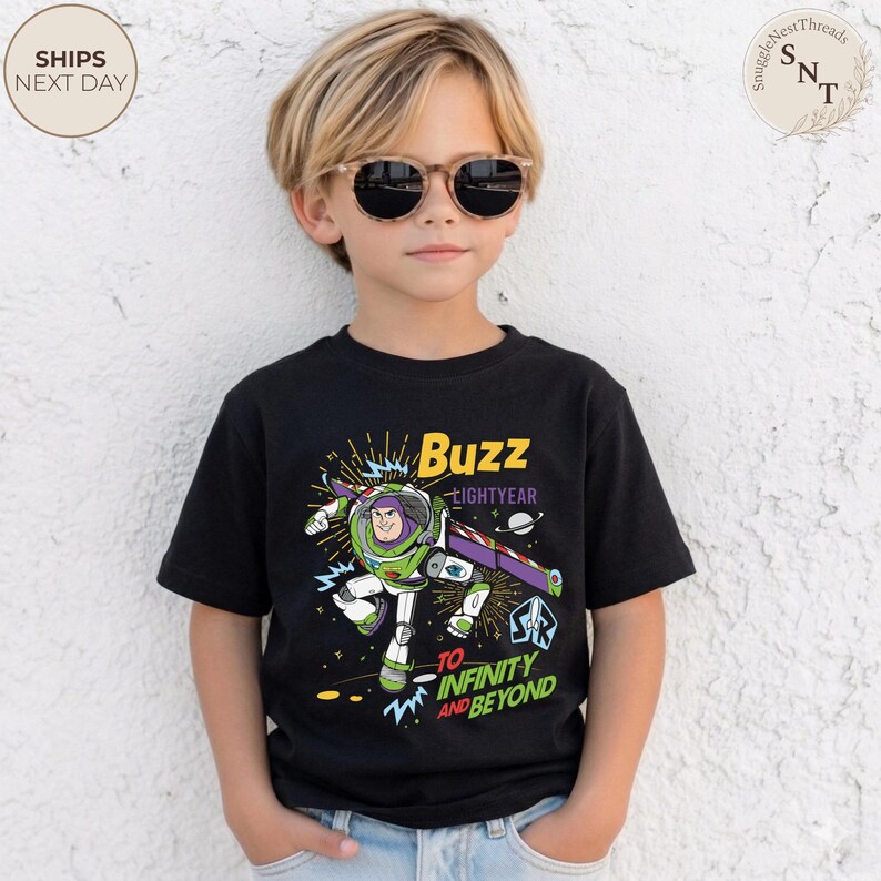 Puede incluir: Camiseta negra de manga corta con un gr&aacute;fico de Buzz Lightyear de Toy Story. El dise&ntilde;o incluye el texto "Buzz Lightyear" y "To Infinity and Beyond" en amarillo y blanco. El personaje est&aacute; representado en su traje espacial verde y blanco.