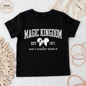 May include: Black t-shirt featuring the text "MAGIC KINGDOM" in white, with "EST. 1971" and "WALT DISNEY WORLD" below. A silhouette of the Disney castle and Mickey Mouse ears are also featured. A classic design for Disney fans.