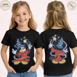 Op de afbeelding: Zwart T-shirt met een cartoon Mickey Mouse tovenaar ontwerp, met een toverstaf met een gloeiende ster. Het ontwerp staat op de voor- en achterkant. Het shirt heeft de tekst "SHIPS NEXT DAY" linksboven.